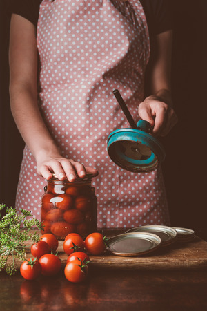 cropped image of woman preparing preserved tomatoes at kitchenの写真素材