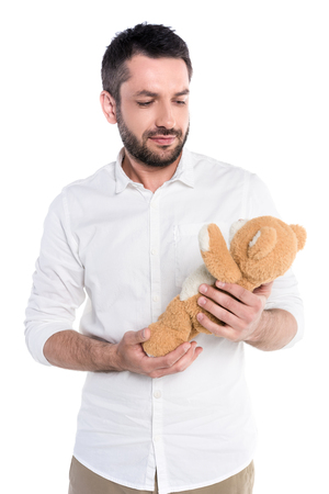 Half-length shot of a young bearded man holding a teddy bearの写真素材