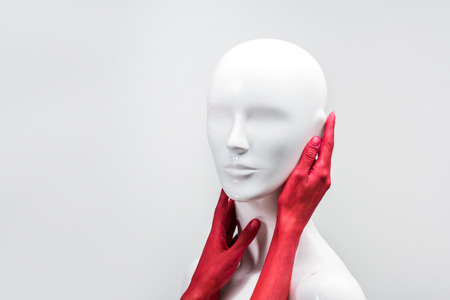 cropped image of woman in red paint touching mannequin neck and face isolated on whiteの写真素材