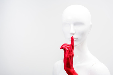 cropped image of woman in red paint showing silence gesture with mannequin isolated on white