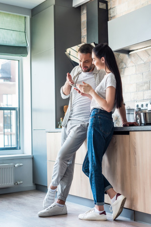 couple using smartphone together in kitchen, smart home conceptの写真素材