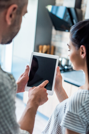 partial view of married couple using digital tablet with blank screen together at home, smart home conceptの写真素材