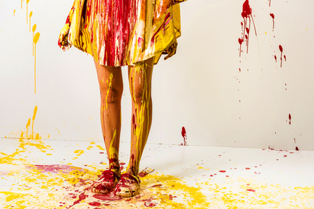 cropped image of woman painted with yellow and red paints standing on floorの写真素材