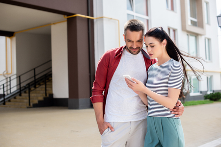 portrait of couple using smartphone on streetの写真素材