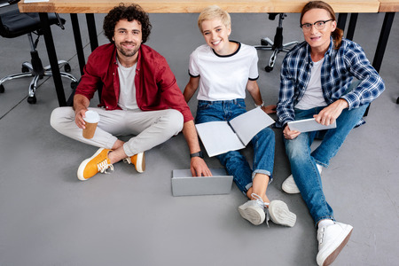 high angle view of young business people working together and smiling at cameraの写真素材