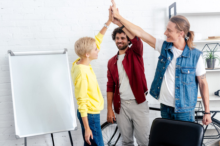 young start up team giving high five while working together neat whiteboard