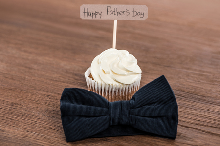 tasty cupcake with bowtie and Happy fathers day inscription on wooden surfaceの写真素材