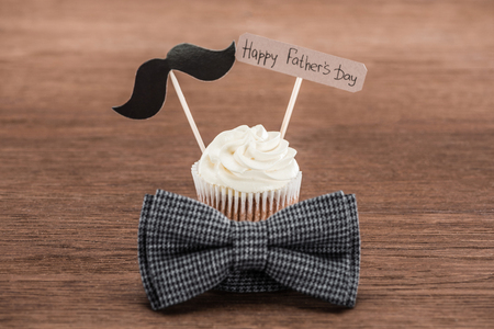 tasty cupcake with mustache sign, bowtie and Happy fathers day inscription on wooden surfaceの写真素材