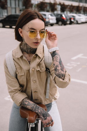attractive stylish tattooed woman standing with bicycle at streetの写真素材