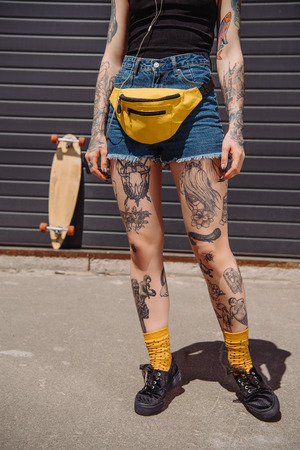 cropped image of stylish tattooed woman with waist bagの写真素材