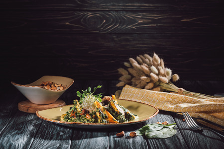 food composition of panikesh with spinach and bowl with cashew nuts on wooden tableの写真素材
