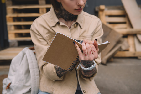 cropped image of tattooed woman writing in textbookの写真素材