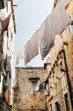 low angle view of laundry and empty narrow city street in Dubrovnik, Croatiaの写真素材