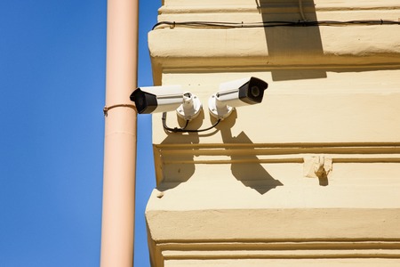close up view of security cameras on yellow building facadeの写真素材