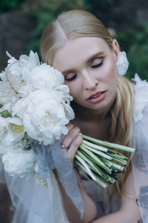 close-up portrait of beautiful young bride in dress with bouquetの写真素材