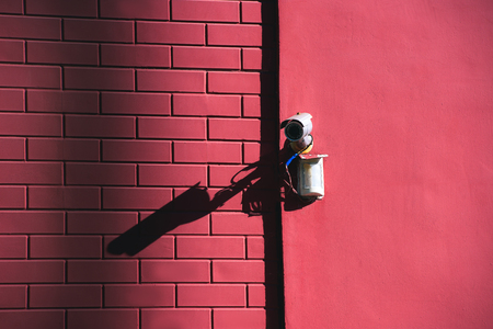 close up view of security camera on pink building facade in sunlightの写真素材