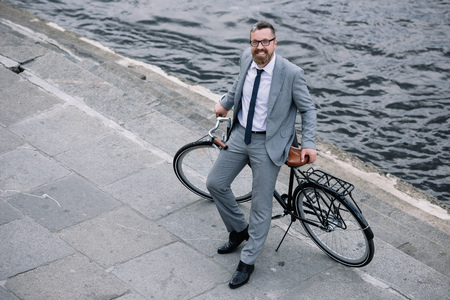 overhead view of businessman standing with bicycle on quay near riverの写真素材