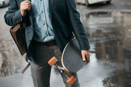 cropped view of stylish man with longboard walking in cityの写真素材