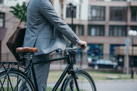 cropped image of businessman standing with bike on street in cityの写真素材