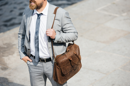 cropped view of businessman with leather bag walking on quayの写真素材