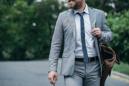 cropped image of smiling businessman walking on street in grey suitの写真素材