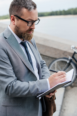 handsome businessman in suit writing in diaryの写真素材