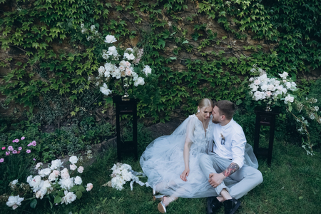 bride and groom sitting on ground in green park togetherの写真素材