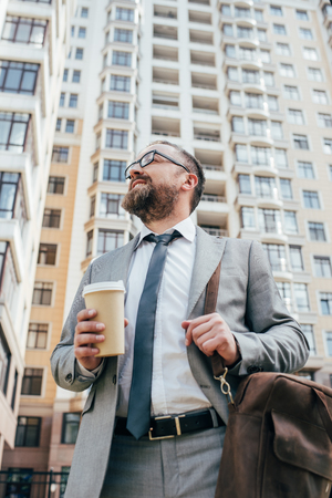 bottom view of businessman in suit with leather bag holding coffee to goの写真素材