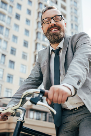 handsome smiling businessman riding bike in cityの写真素材