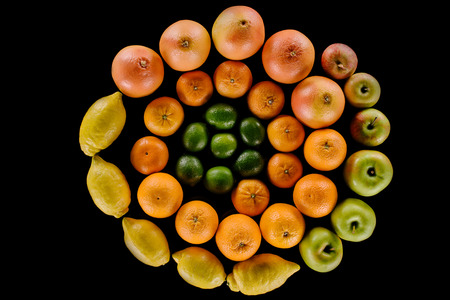 top view of various ripe citrus fruits composition in spiral shape isolated on blackの写真素材