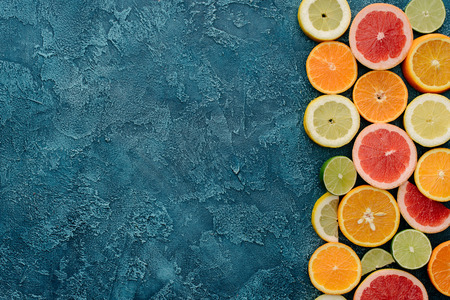 top view of fresh citrus fruits slices on blue concrete surface