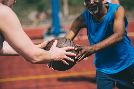 partial view of man giving basketball ball to old african american friendの写真素材