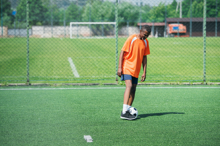 african american elderly man training with football ball in fieldの写真素材