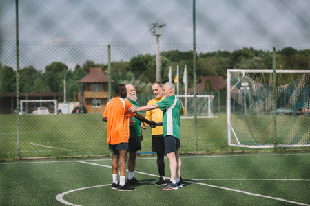 interracial elderly football players after match on green fieldの写真素材
