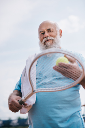 low angle view of old man with towel and tennis equipment in handsの写真素材