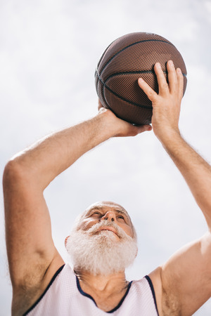 low angle view of elderly bearded man with basketball ball in handsの写真素材