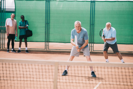 selective focus of old sportsmen playing tennis on courtの写真素材