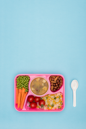 top view of tray with kids lunch for school and spoon isolated on blueの写真素材