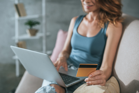 cropped image of woman shopping online with laptop and credit card at homeの写真素材