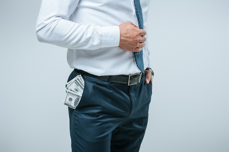 cropped image of financier standing with money in pocket isolated on greyの写真素材