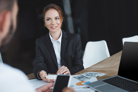 financiers looking at each other and holding smartphone and calculator in officeの写真素材