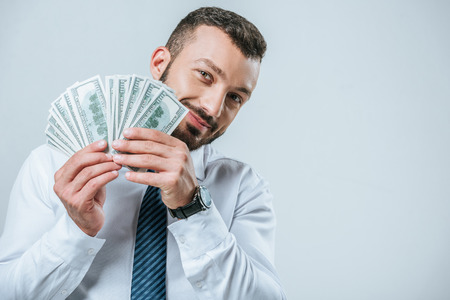 smiling financier showing dollars isolated on grey