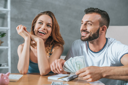 smiling couple planning family budget and looking away in living roomの写真素材