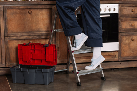 cropped shot of repairwoman standing on stepladder at kitchenの写真素材