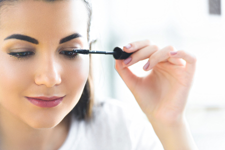 portrait of attractive young woman applying black mascara on eyelashesの写真素材