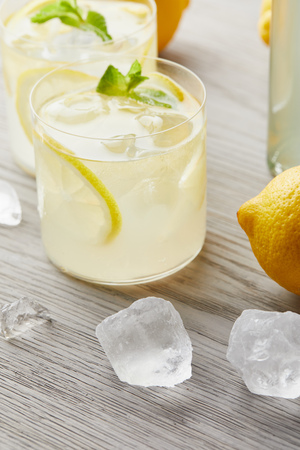 close-up shot of fresh glasses of lemonade with ice and lemon on wooden surfaceの写真素材