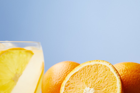 glass of refreshing lemonade with oranges on wooden tableの写真素材