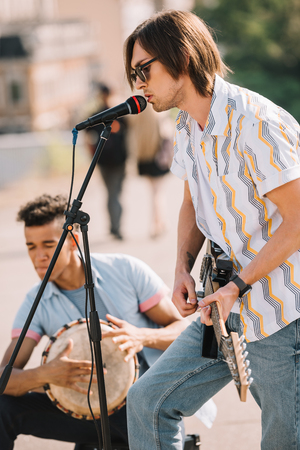 Young happy buskers drummer and guitarist playing music at city streetの写真素材