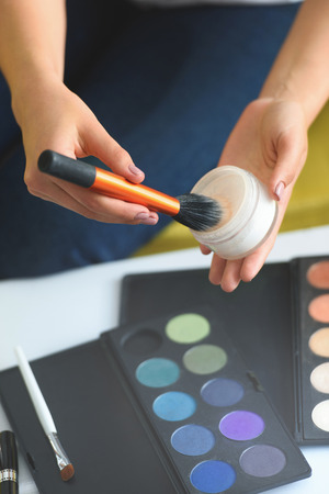 cropped shot of woman holding face powder and makeup brush in hands at homeの写真素材