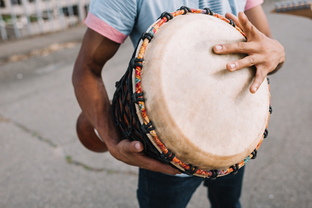 Cropped view of african american street musician playing djembe in cityの写真素材